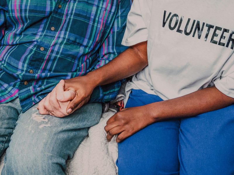 A Person Wearing Volunteer Shirt Holding a Persons Hand