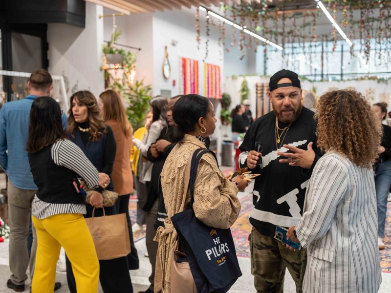 People standing around in a brightly lit store with hanging plants.